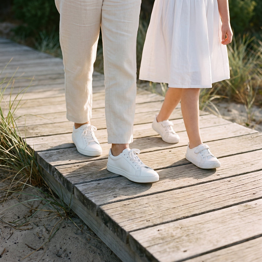 Grandmother and granddaughter in white sneakers on the beach boardwalk