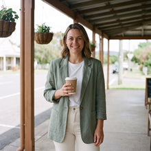 Woman in a sage linen blazer outside a cafe