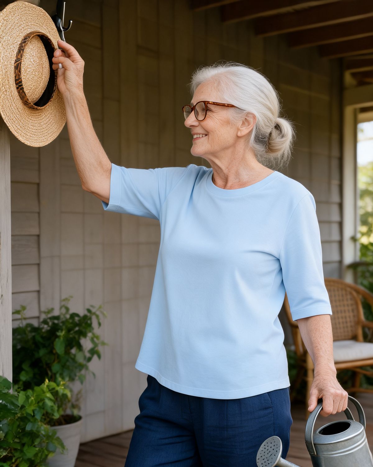 Woman reaching up on her verandah in the Maeve tee in Blue, upper arm covered by the sleeve